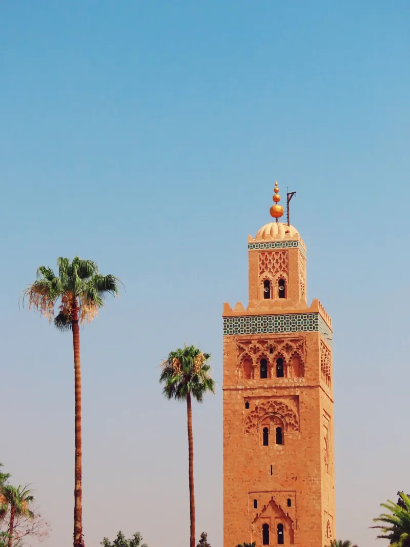 Koutoubia Mosque minaret in Marrakech framed by palm trees at dusk