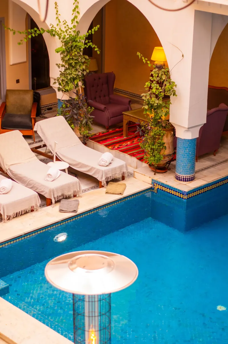 Small turquoise plunge pool in a riad courtyard with sun loungers under the arcades