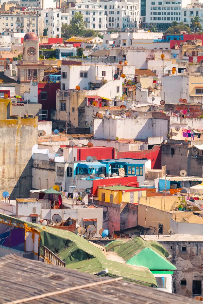 Dense white and pastel rooftops of the Tangier medina sloping down toward the sea